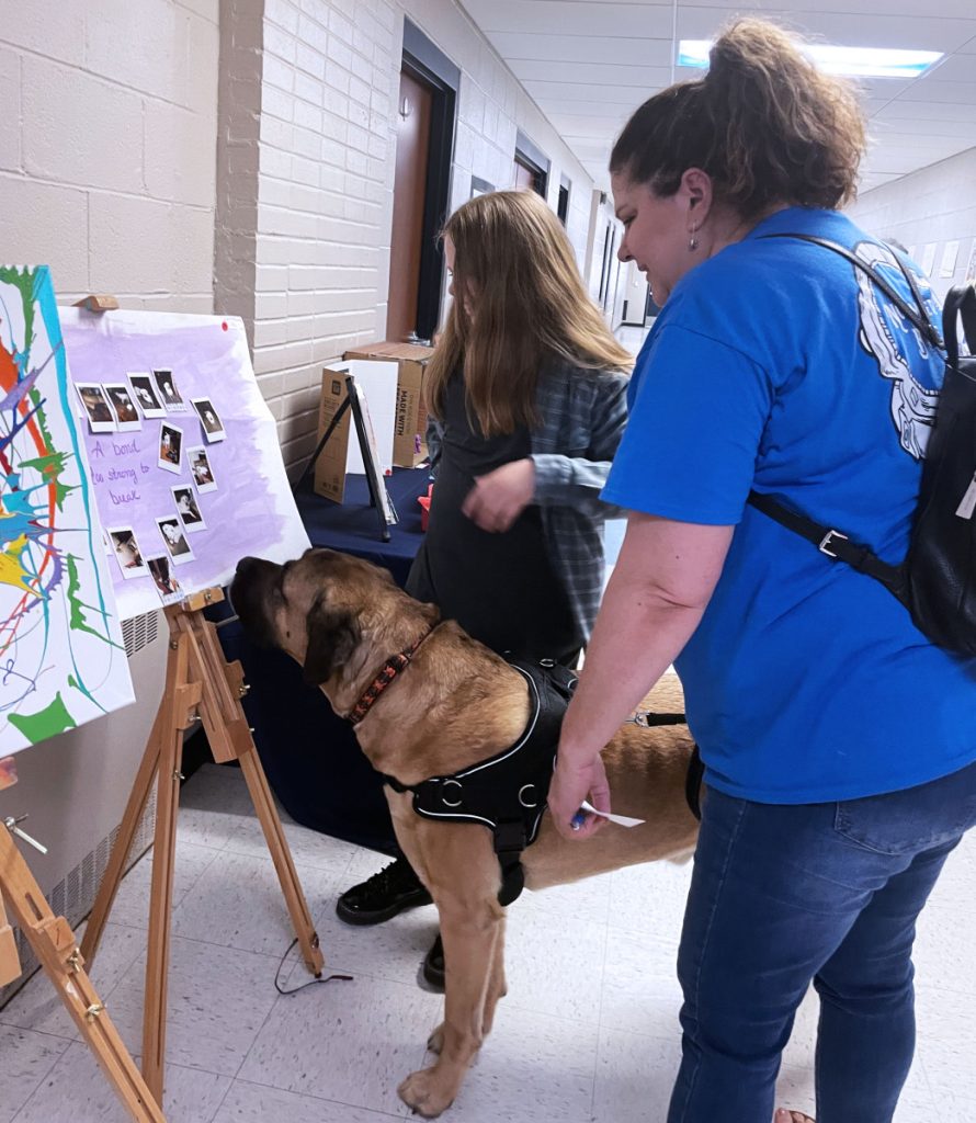 Student artist Liberty Robinson, left, shows her artwork to Marshall County Schools Superintendent Dr. Shelby Haines and her dog, Duncan. 