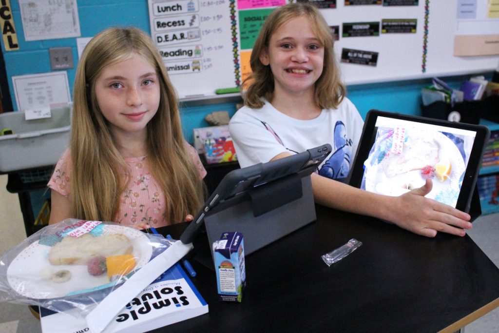 Pictured from left: Central Elementary 5th graders Arianna Cepeda and Karlie Anderson conduct a mold terrarium experiment, using their iPads, to discover how various foods decompose at a different rate. They take daily pictures to record and compare the changes.