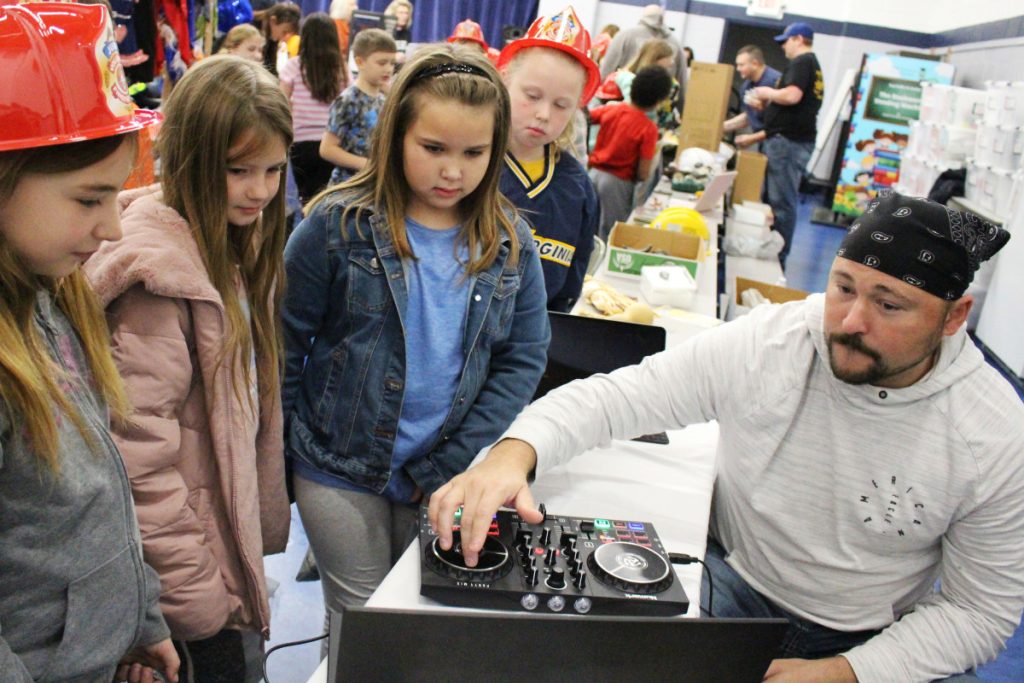 DJ Daner, far right, shows, from left, Central Elementary third graders Jordynn Kittle, Harper Henry, Jurnee Hicks and Brynn Bowie how to mix songs using an audio board.   